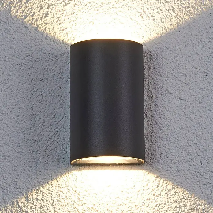 Lucande LED Wandleuchte aussen in anthrazit, transparent, Aussenlampe Wand -  - Dunkelgraue zylindrische Außenwandleuchte strahlt Licht nach oben und unten an strukturierter Wand.