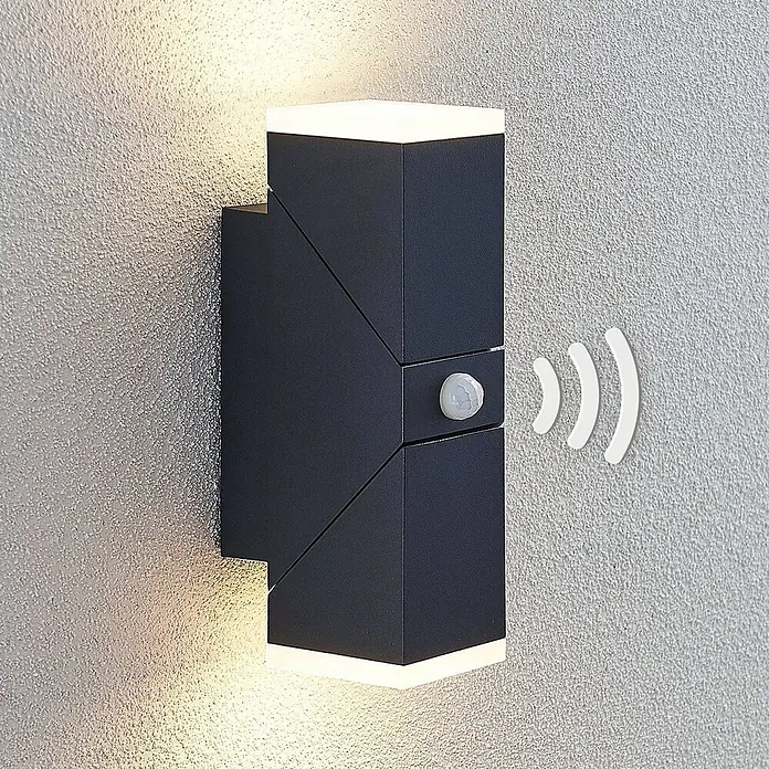 Lindby LED Wandleuchte aussen in anthrazit, weiß satiniert, mit -  - Anthrazitfarbene geometrische Außenwandleuchte mit Up/Down-Beleuchtung und integriertem Bewegungsmelder an einer strukturierten Wand.