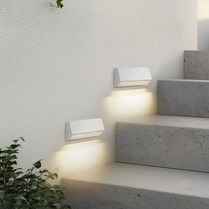 Lindby LED Wandleuchte aussen in weiß, Aussenlampe Wand -  - Zwei weiße Außenwandleuchten an einer Wand, die eine Betontreppe warm beleuchten.