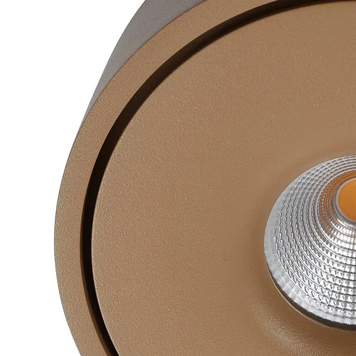 Arcchio Deckenleuchte Rotari - braun / rost, braun / rost - Nahaufnahme eines runden, bronzefarbenen LED-Strahlers mit texturierter Linse, die eine orangefarbene Lichtquelle zeigt.