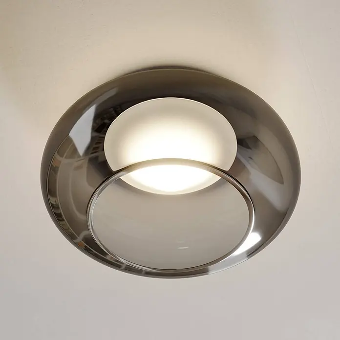 Lucande Deckenleuchte Mijo - alu / grau / zink - Eine moderne Deckenleuchte mit glänzendem rauchgrauem Außenring und zwei mattweißen Innendiffusoren, einer beleuchtet.