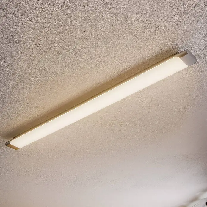 Arcchio LED Deckenlampe in weiß, silber, Deckenleuchte -  - Rechteckige LED-Deckenleuchte mit weißem Diffusor und silbernen Enden, leuchtend an einer strukturierten Decke.