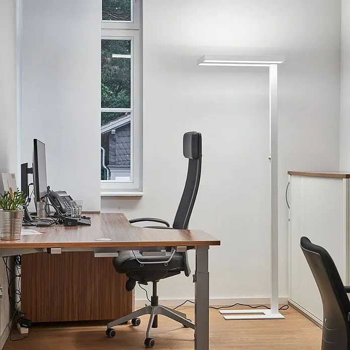 Arcchio LED Büro Stehlampe dimmbar weiß, Bürolampe Stehleuchte 6000lm -  - Eine moderne weiße LED-Stehleuchte beleuchtet einen Büroschreibtisch mit indirektem und direktem Licht.