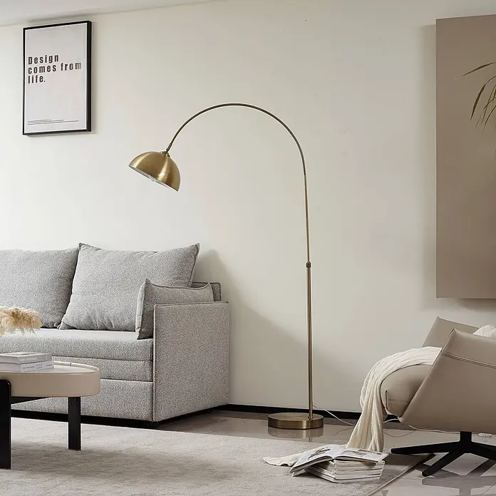 Lindby Stehlampe in messing, Bogenlampe Wohnzimmer -  - Messingfarbene Bogenstehleuchte in einem modernen Wohnzimmer, beleuchtet Sofa und Sessel.