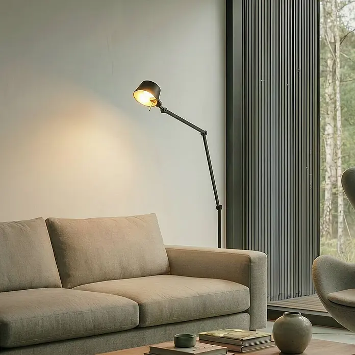 Lucande Stehlampe Büro in schwarz, gold, Büroleuchte -  - Schwarze, verstellbare Stehlampe spendet warmes Licht in modernem Wohnzimmer neben beigem Sofa.