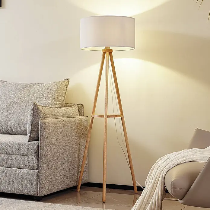 Lindby Stehlampe Wohnzimmer, Tripod in weiß, holz, Stehleuchte -  - Moderne Stehlampe mit weißem zylindrischem Schirm und hellem Holzstativ, die warmes Licht in einem Wohnzimmer spendet.