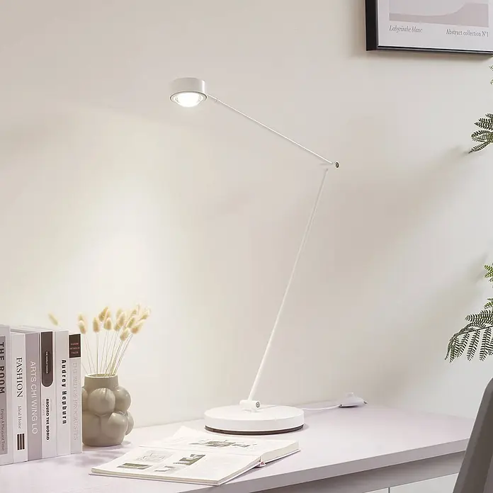 Lindby Stehleuchte Jyla - weiß / opal, weiß / opal - Eine weiße, moderne Schreibtischlampe mit verstellbarem Arm und rundem Fuß beleuchtet einen Schreibtisch mit Büchern und einer Vase.