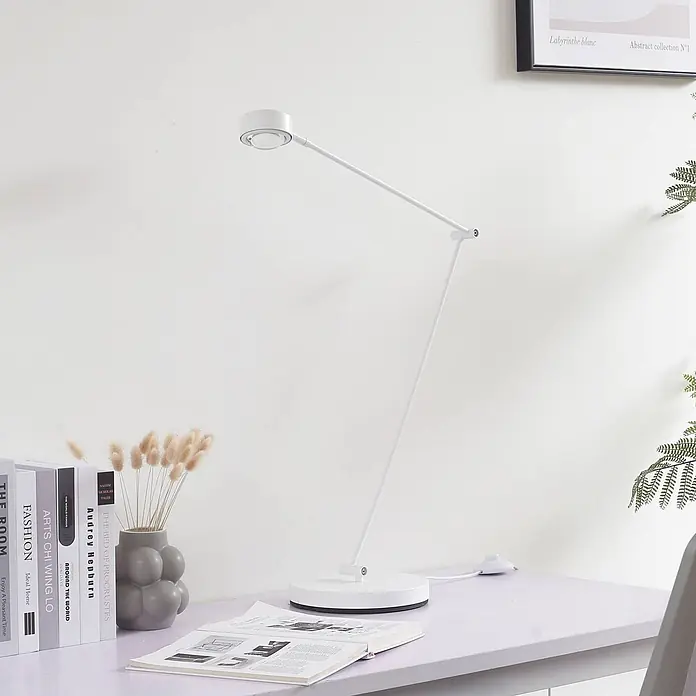 Lindby Stehleuchte Jyla - weiß / opal, weiß / opal - Weiße moderne Schreibtischlampe mit verstellbarem Arm und rundem Fuß, beleuchtet ein Buch auf einem hellen Schreibtisch.