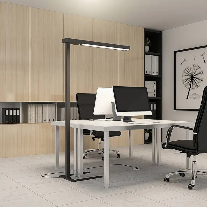 Arcchio Stehleuchte Susi - schwarz, schwarz - Eine hohe, dunkelgraue, rechteckige Stehleuchte beleuchtet einen modernen Büroschreibtisch mit Computern.