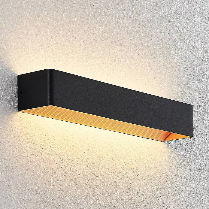 Arcchio LED Wandleuchte innen in schwarz, gold, Wandlampe -  - Schwarze rechteckige Wandleuchte mit goldgerippter Innenseite, die warmes Licht an eine Wand wirft.