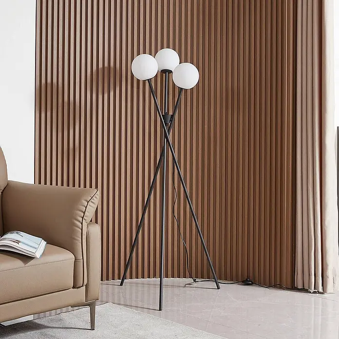 Lucande Stehleuchte Visata - schwarz, G9 - Eine moderne schwarze Stativ-Stehlampe mit drei kugelförmigen weißen Leuchten, in einem Wohnzimmer.