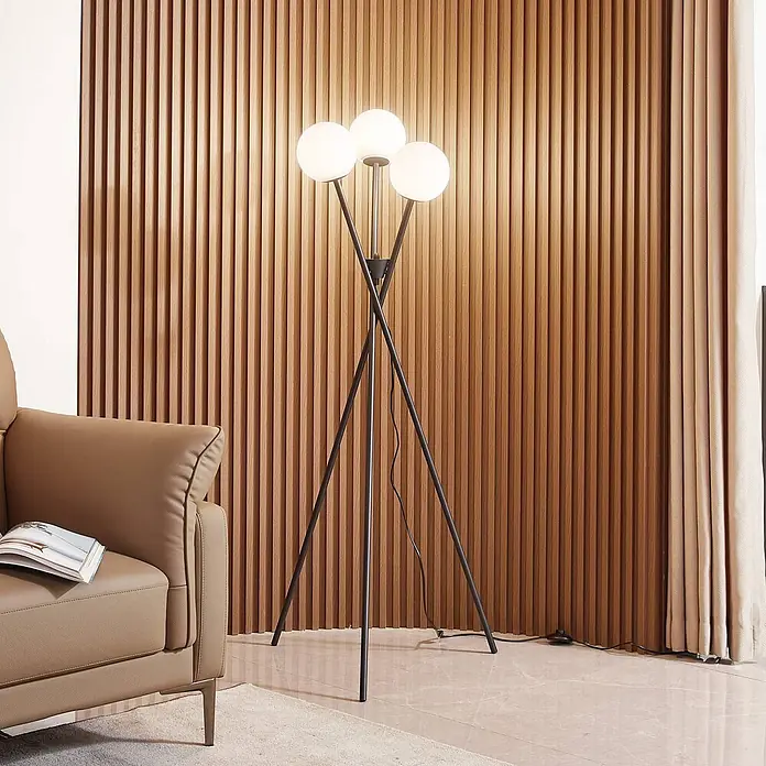 Lucande Stehleuchte Visata - schwarz, G9 - Schwarze Dreibein-Stehlampe mit drei weißen Kugel-Lampenschirmen in einem modernen Wohnzimmer.