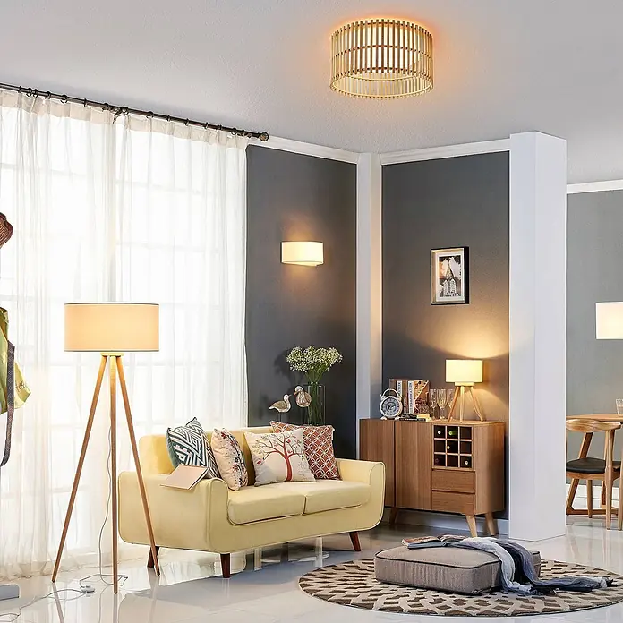 Lindby Stehlampe Dreibein Stoff weiß, Holz hell, mit Fußschalter -  - Deckenleuchte aus Holzlamellen in Trommelform, die ein modernes Wohnzimmer erhellt.