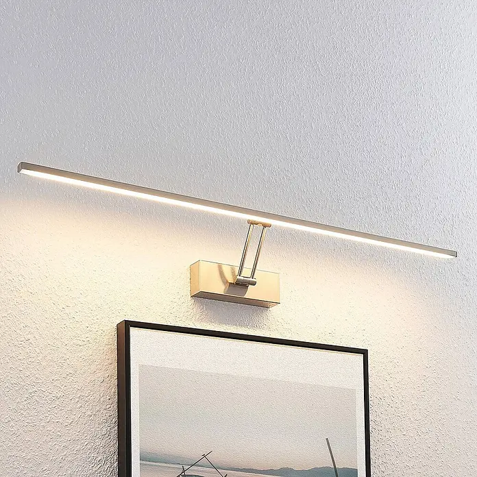 Lucande LED Bilderleuchte in nickel matt, Wandleuchte Bilderlampe -  - Gebürstete Metall-LED-Bilderleuchte an einer strukturierten Wand, die ein gerahmtes Bild beleuchtet.