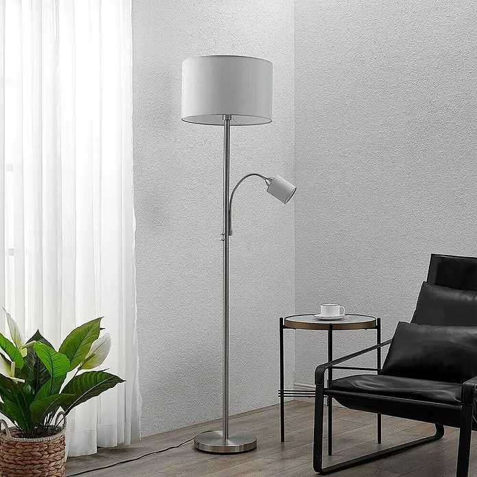 Lindby Stehlampe Wohnzimmer in nickel satiniert, grau, Stehleuchte -  - Gebürstete Nickel-Stehlampe mit Trommelschirm und verstellbarer Leselampe, in einem Wohnbereich platziert.