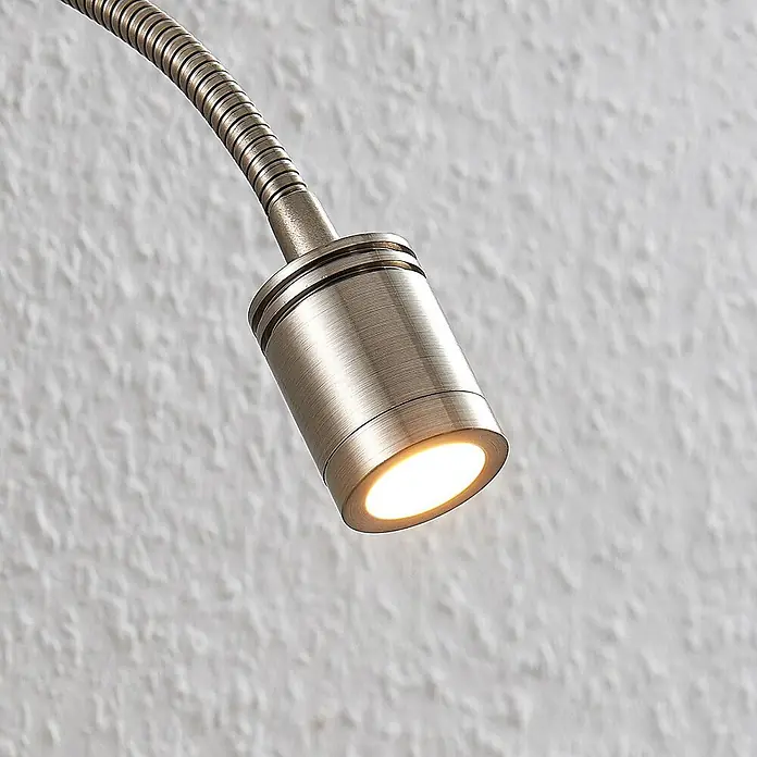 Lindby LED Wandleuchte innen in nickel satiniert, Wandlampe -  - Nahaufnahme eines gebürsteten LED-Spotlights aus Antikmessing mit Schwanenhals und warmem, leuchtendem Licht.