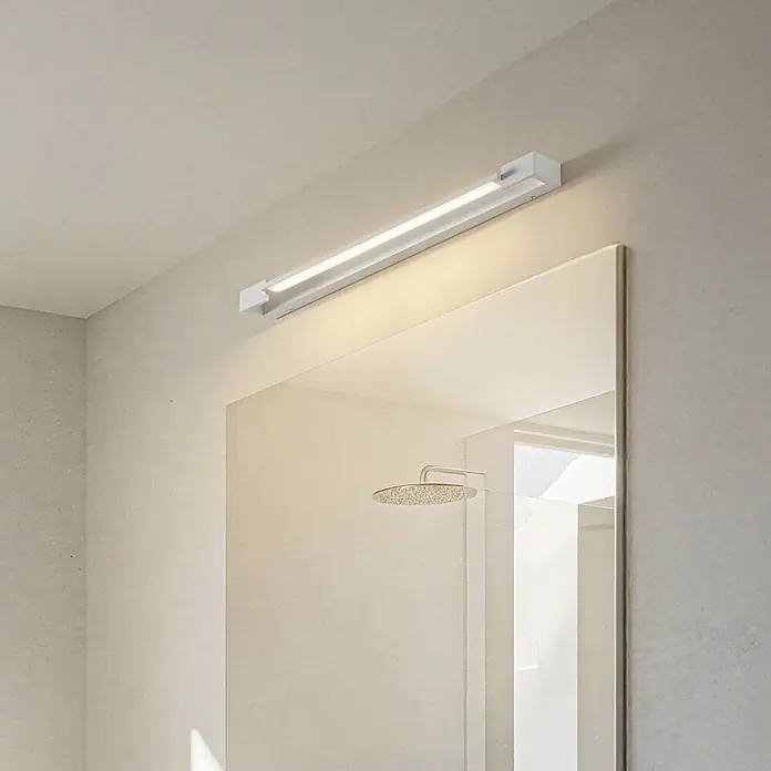 Arcchio LED Wandleuchte innen in weiß, Wandlampe -  - Weiße, lineare LED-Leuchte spendet Licht über einem Spiegel in einem modernen Badezimmer.