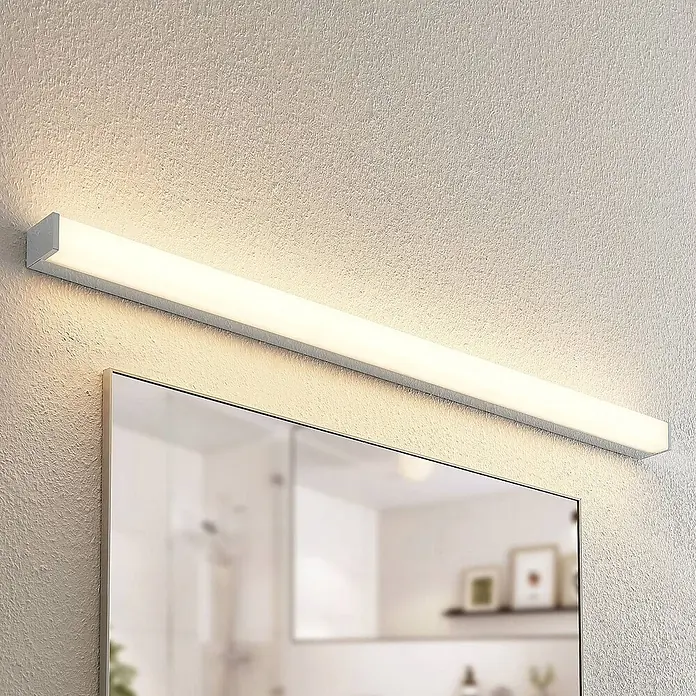 Lindby LED Wandleuchte innen in weiß, chrom, up down Wandlampe -  - Lineare LED-Spiegelleuchte in Weiß/Silber, die eine strukturierte Wand über einem Spiegel beleuchtet.