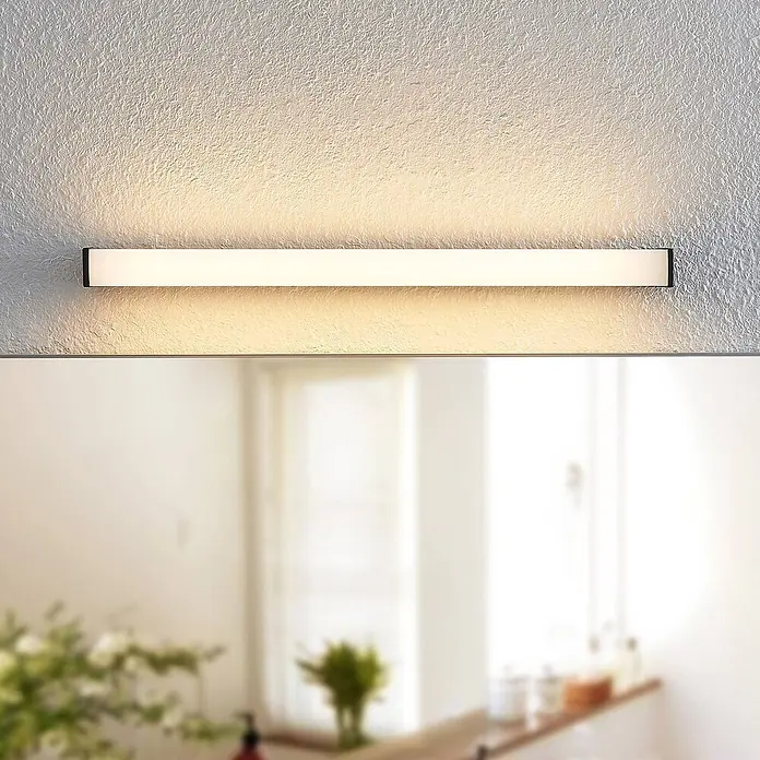 Lindby LED Wandleuchte innen in schwarz matt, weiß, Wandlampe -  - Rechteckige LED-Spiegelleuchte mit schwarzem Rahmen und weißem Diffusor, über einem Spiegel an einer strukturierten Wand, sorgt für gleichmäßige Beleuchtung.