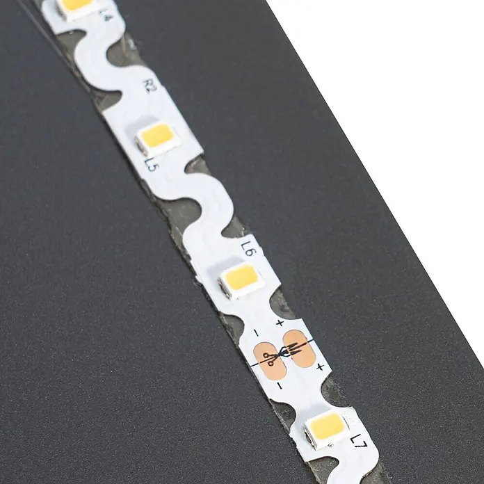 Lucande LED Wandleuchte innen in schwarz, silber, Wandlampe -  - Segmentierter weißer LED-Streifen mit zahlreichen kleinen rechteckigen LEDs und Schnittlinien. Die flexible Platine zeigt Polaritäts- und Bauteilmarkierungen.