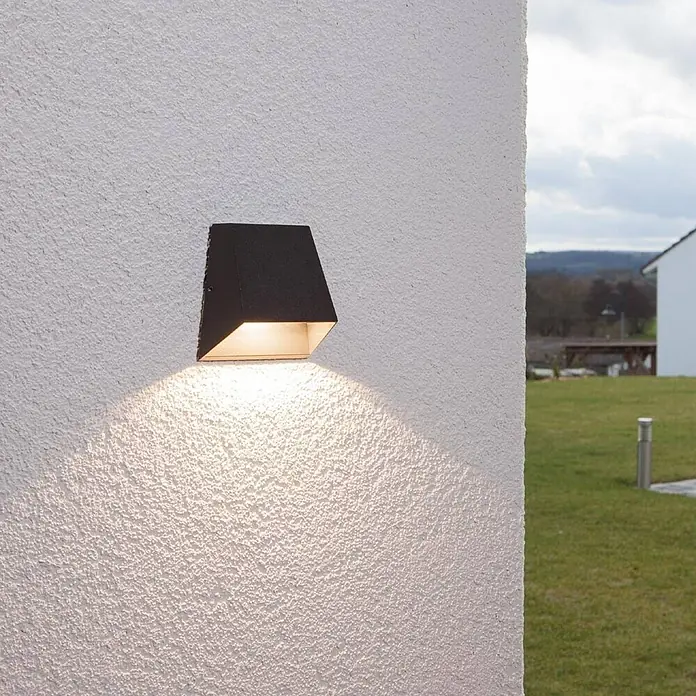 Lucande Außenwandleuchte Hanno - schwarz, schwarz, IP54 - Dunkle Outdoor-Wandleuchte an einer strukturierten Wand, die warmes Licht nach unten wirft.