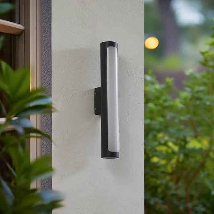 Lucande LED Wandleuchte aussen in anthrazit, weiß, Aussenlampe Wand -  - Schwarz zylindrische Außenwandleuchte mit weißem Diffusor, vertikal an einer hellen Außenwand montiert.