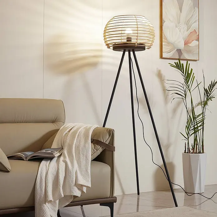 Lindby Stehlampe Wohnzimmer, Tripod in holz, schwarz, Stehleuchte -  - Dreibein-Stehlampe mit kugelförmigem, naturbelassenem Holzlamellenschirm und schwarzen Metallbeinen, beleuchtet ein gemütliches Wohnzimmer.