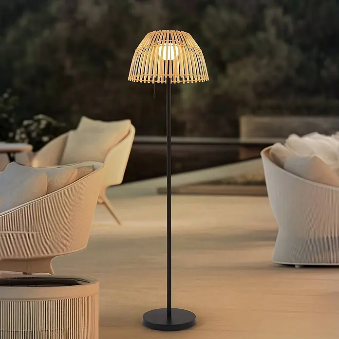 Lucande LED Solar Stehlampe Outdoor in schwarz, dimmbar up down Stehleuchte -  - Hohe Outdoor-Stehleuchte mit natürlichem Bambusgeflecht-Schirm, beleuchtet eine Terrassen-Lounge bei Dämmerung.