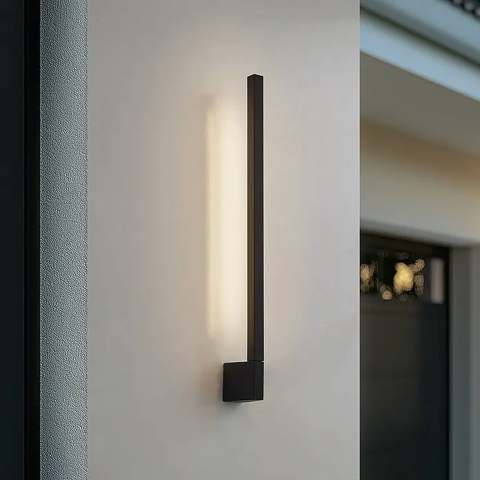 Lindby LED Wandleuchte aussen in schwarz, weiß, Aussenlampe Wand -  - Elegante schwarze lineare Wandleuchte wirft warmes Licht auf eine helle Wand.