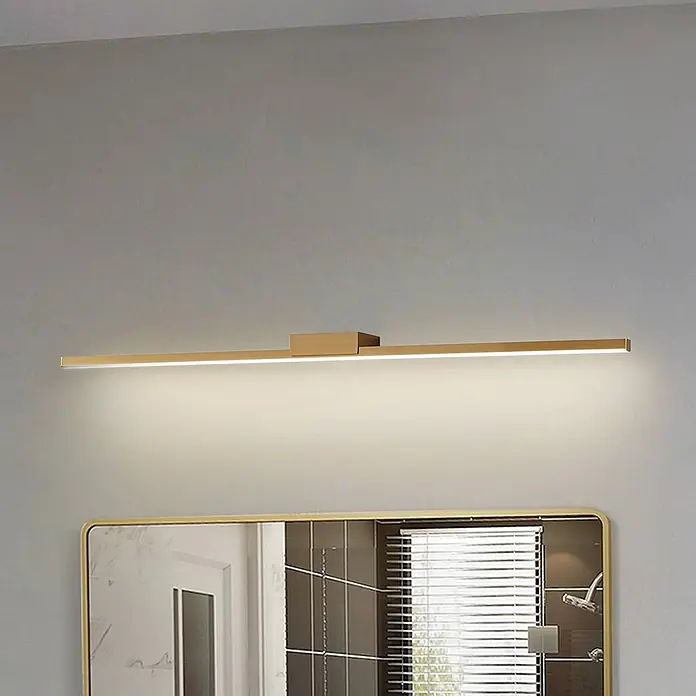 Lucande LED Wandleuchte innen in kupfer, Wandlampe -  - Lange, schlanke goldene LED-Spiegelleuchte über einem Spiegel beleuchtet.