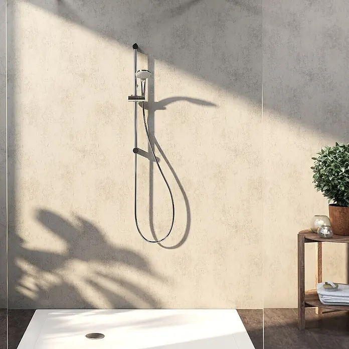 Ideal Standard Brause-Set - Chrom - Ein modernes Duschsystem aus Chrom mit Handbrause und Schlauch, an einer strukturierten Wand über einer weißen Duschwanne im Bad montiert.
