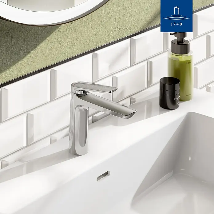 Villeroy & Boch Waschtischarmatur - Chrom, Hochglänzend - Polierte Chrom-Waschtischarmatur auf einem weißen Keramikwaschbecken, mit verschiedenen Pflegeprodukten daneben.