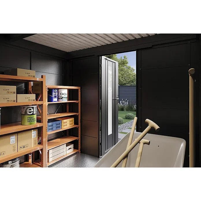 Wolff Finnhaus Gartenhaus Hakon Master Line - Außenmaß inkl. Dachüberstand (B x T): 264 x 272 cm, Metall, Anthrazit - Ein organisiertes schwarzes Lagerhausinterieur mit orangefarbenen Regaleinheiten, gestapelten Kartons, Farbdosen und Zubehör, mit offener Tür zu einem grünen Garten.