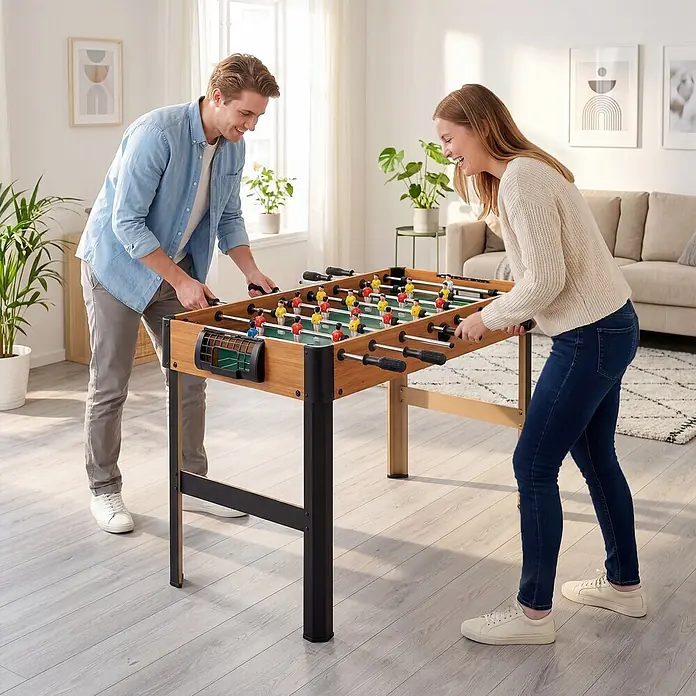HOMCOM-Tischkicker-118L x 104B x 69H cm -  - Ein Holzkicker mit schwarzen Beinen, der von zwei Personen in einem Wohnzimmer gespielt wird.