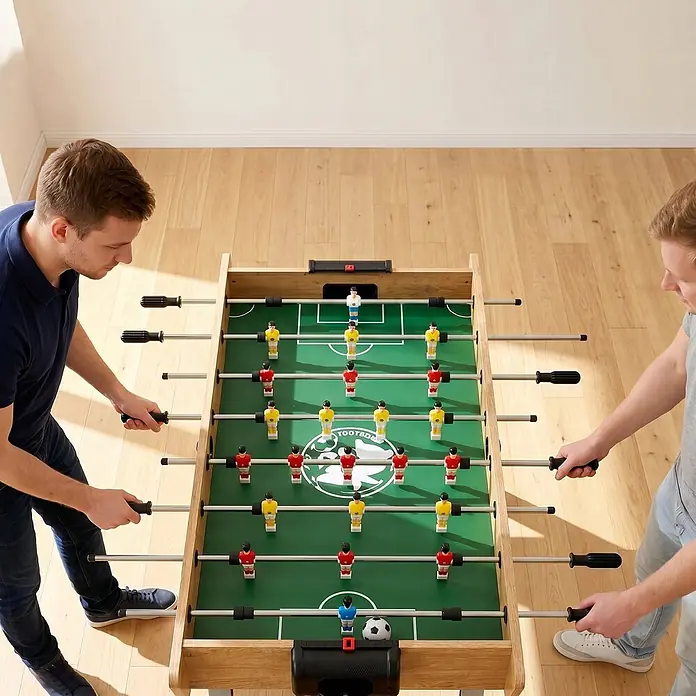 Sportnow Tischkicker - L x B x H: 121 x 87 x 77 cm, Naturholz - Zwei Männer spielen Kicker an einem Holztisch mit grünem Feld und roten und gelben Spielern.