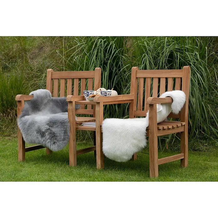 Bene Living Gartenbank Feierabend - Teakholz, Natur - Zwei Holzgartenstühle mit grauen und weißen Kunstfelldecken und einem Beistelltisch mit herbstlichen Dekorationen und Tassen.