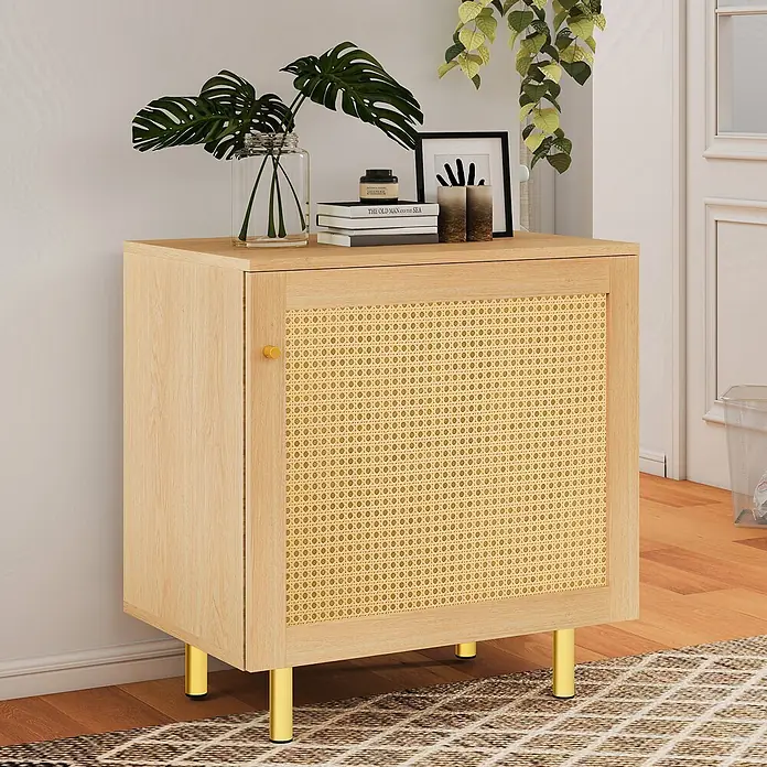 SONNENH Kommode - Natur - Heller Holzschrank mit Rattantür, goldenem Griff und goldenen Beinen, dekoriert mit Büchern und Pflanzen im Wohnbereich.