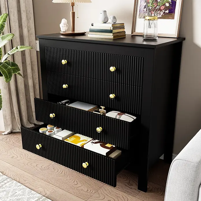 SONNENH Kommode - Schwarz/Gold, Anzahl Schubladen: 5 Stk. - Eine schwarze Kommode mit geriffelten Schubladenfronten und goldenen Knöpfen, mit geöffneten Schubladen in einem Wohnraum.