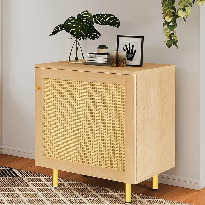 SONNENH Kommode - Natur - Helles Holzschrank mit geflochtenem Rattantürpaneel und goldenen Metallbeinen und Griff, in einem Wohnzimmer arrangiert.