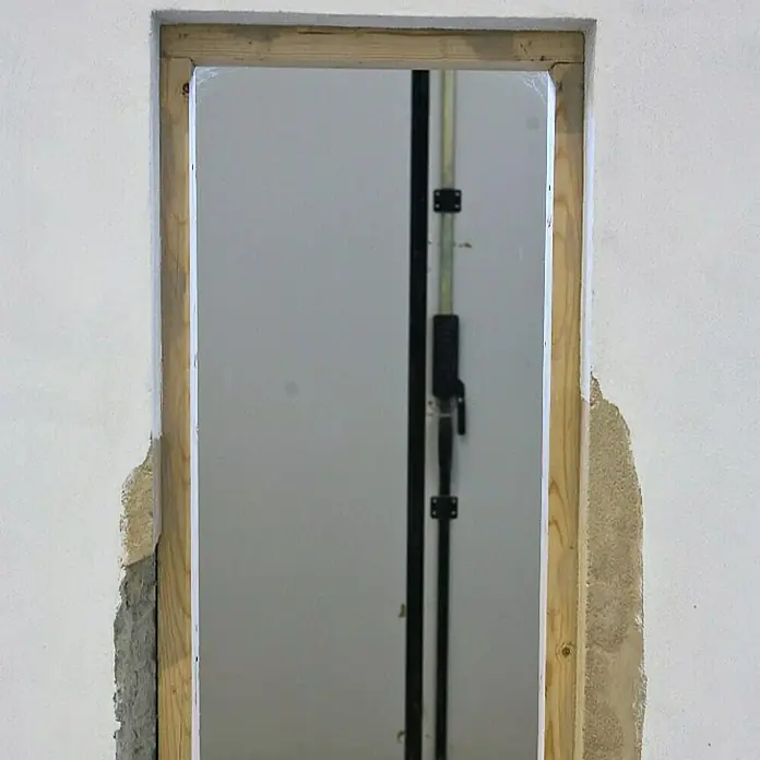 Profi Depot Schnellreparatur-Mörtel - 25 kg - Bild eines unfertigen Türrahmens mit freiliegendem Holz und Beschädigungen an der umgebenden Wand.