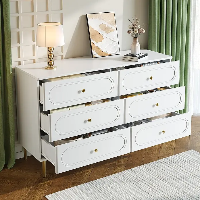 SONNENH Kommode - Weiß, Anzahl Schubladen: 6 Stk. - Weißes Sideboard mit goldenen Griffen und Beinen, mit sechs geöffneten Schubladen voller Gegenstände, in einem Innenraum.