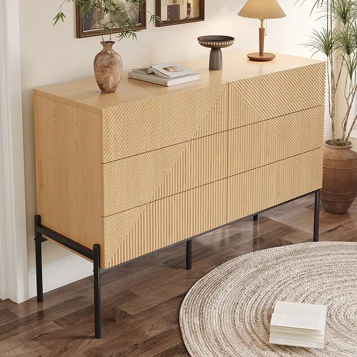 SONNENH Kommode - Natur/Schwarz, Anzahl Schubladen: 6 Stk. - Helles Holz Sideboard mit texturierten, geometrisch gemusterten Schubladen auf schwarzen Metallbeinen, in einem Wohnraum arrangiert.