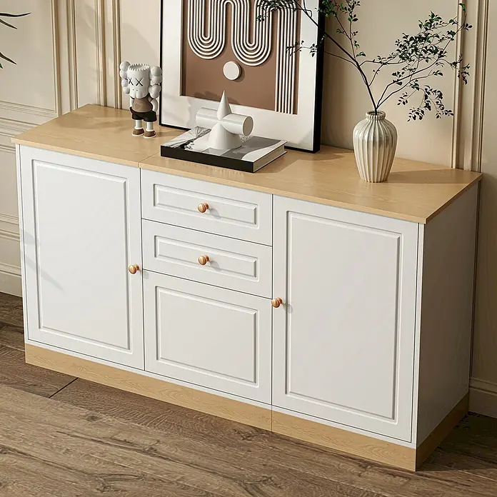 SONNENH Kommode - Weiß/Natur, Anzahl Schubladen: 2 Stk. - Weißes Sideboard mit heller Holzplatte und -sockel, zwei Türen und drei Schubladen mit kupferfarbenen Knäufen, in einem Wohnraum.
