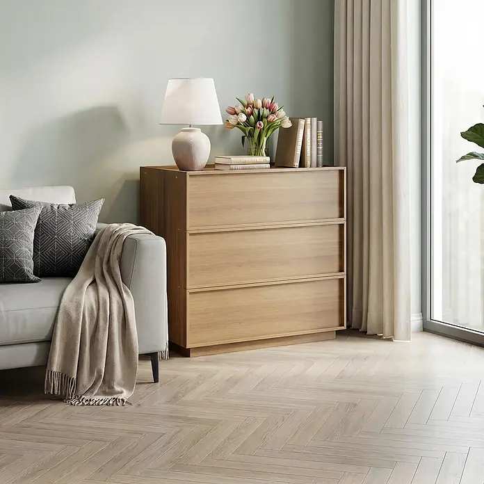 SONNENH Kommode - Eichenoptik, Anzahl Schubladen: 3 Stk. - Helle Holzkommode mit drei Schubladen, dekoriert mit Lampe, Büchern und Blumen in einem modernen Wohnzimmer.