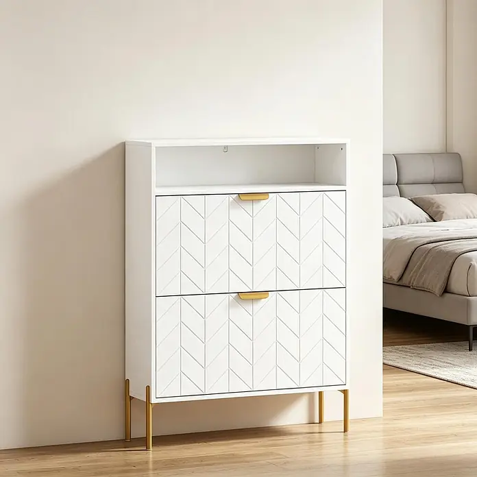 SONNENH Schuhschrank - Weiß/Gold - Weiße Kommode mit Fischgrätmuster, goldfarbenen Griffen und Beinen, und offener Ablage, im Schlafzimmer.