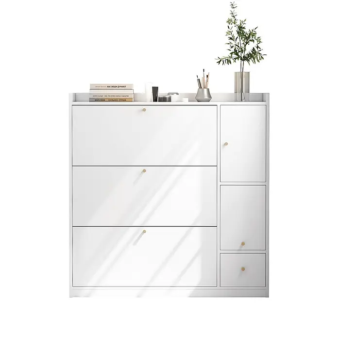 SONNENH Schuhschrank - Weiß - Weißer moderner Schuhschrank mit drei Kippfächern und drei Seitenfächern, versehen mit goldfarbenen Knöpfen. Bücher und eine Pflanze stehen darauf.