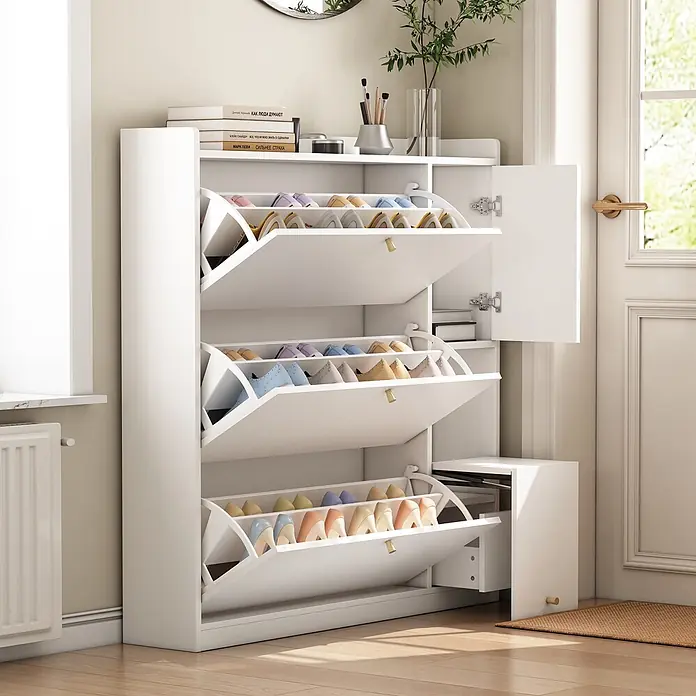 SONNENH Schuhschrank - Weiß - Weißer Garderobenschuhschrank mit drei kippbaren Fächern voller bunter Schuhe und einem Seitenfach, neben Tür und Fenster.