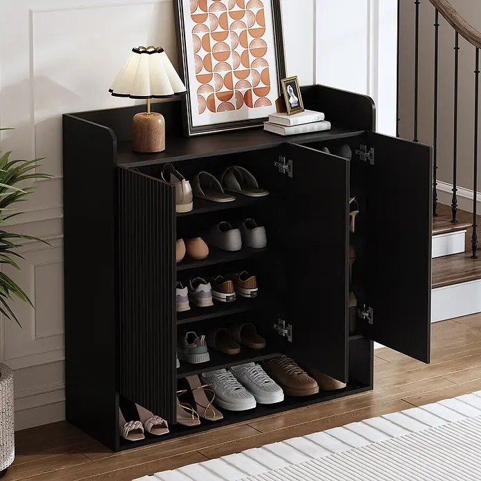 SONNENH Schuhschrank - Schwarz - Schwarzer Schuhschrank mit verschiedenen Schuhen, obenauf eine Lampe und gerahmte Kunst, in einem Eingangsbereich platziert.