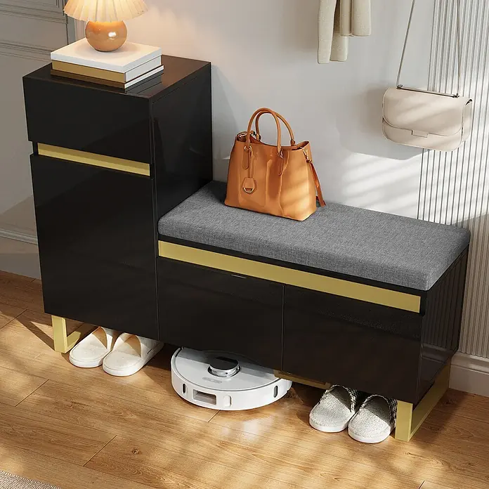 SONNENH Schuhschrank - Schwarz/Gold - Schwarzer Schuhschrank mit goldenen Akzenten und grauer Sitzauflage, im Flur mit Hausschuhen und Saugroboter darunter.
