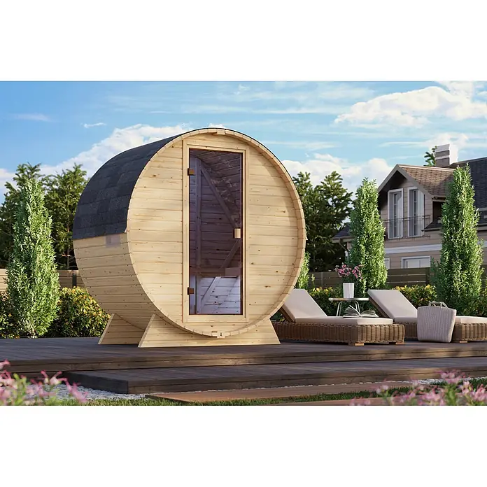 Karibu Saunahaus Samantha - Ohne Ofen, L x B x H: 140 x 225 x 229 cm - Helle Holzfasssauna mit dunklem Dach und Glastür auf einer Holzterrasse im Garten, umgeben von Liegestühlen.